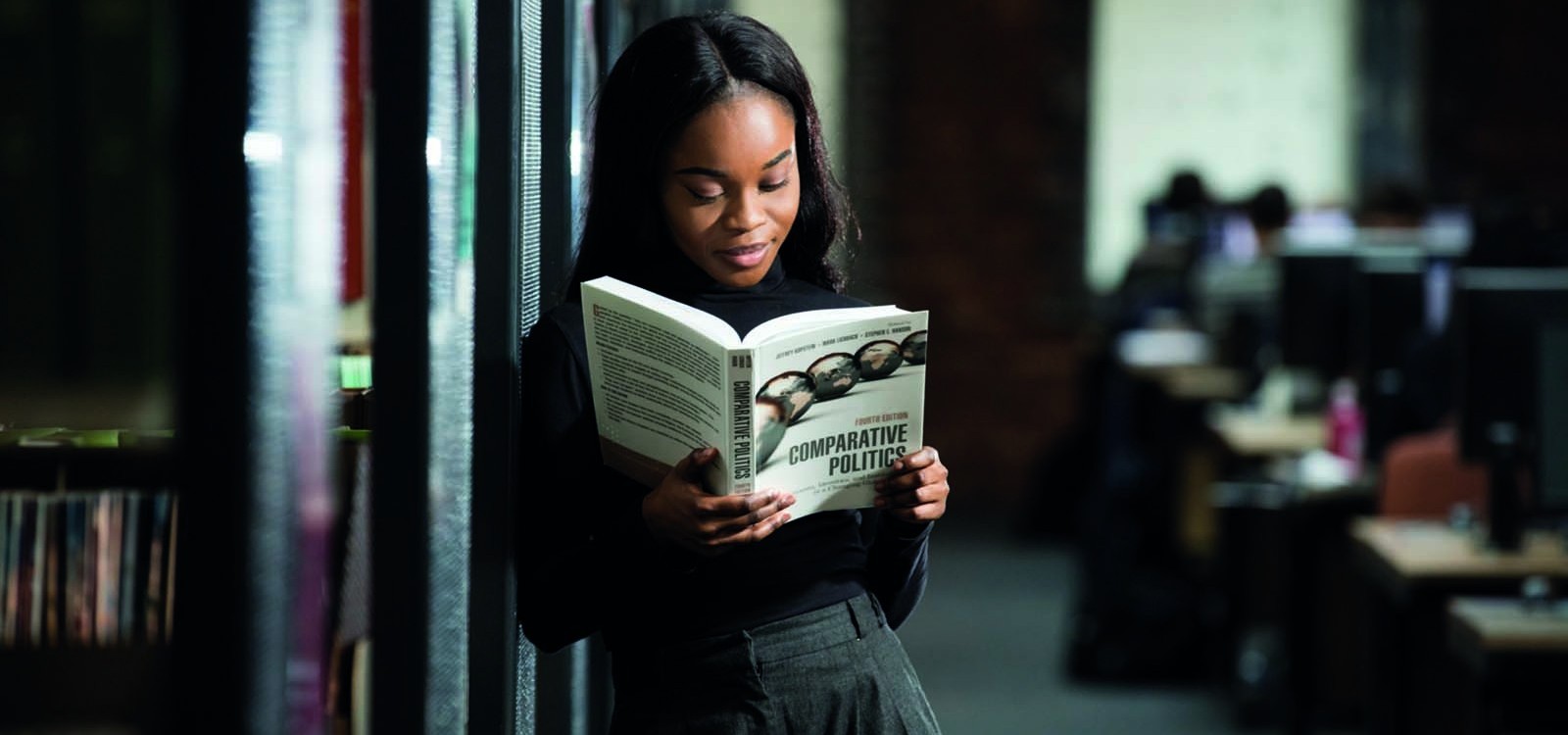 Black student reading a politics book in the library